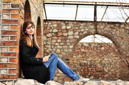 pretty teen girl reading  outdors on the brick windowの写真素材