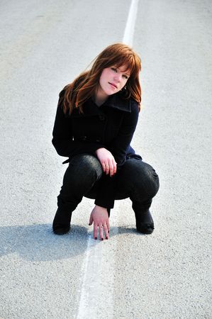 redheaded pretty girl sitting on the roadの写真素材