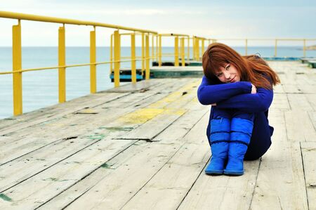 Young redheaded girl on a pier near the seaの写真素材