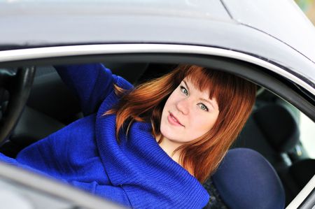 redheaded teen girl drivering a dark car の写真素材