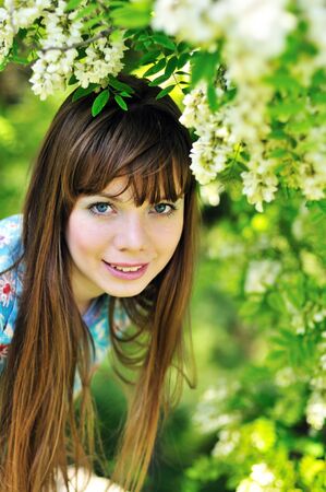 happy pretty girl stending  near blossom of  acaciaの写真素材