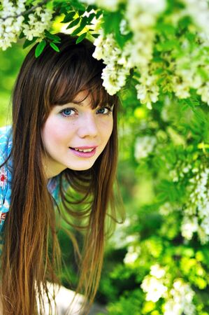 face of cheerful pretty girl standing near blossom of acacia の写真素材