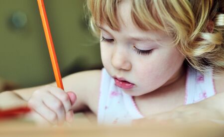 serious little girl drawing in soft selective focus の写真素材