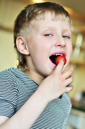 little funny boy is enjoying strawberryの写真素材