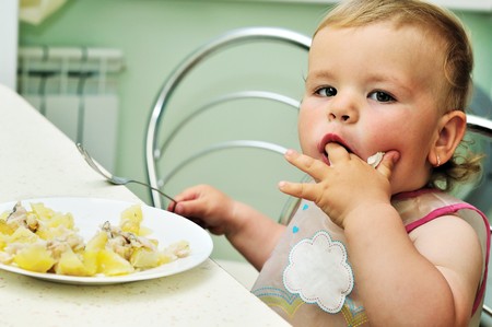 sweet baby girl eating on her ownの写真素材