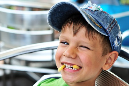 little boy enjoying french fries  in cafeの写真素材