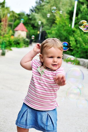 baby girl catching soap bubbles in the parkの写真素材