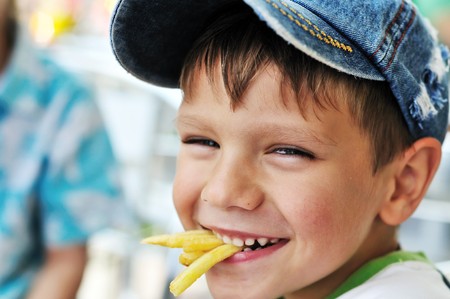 little boy eating french fries in cafe の写真素材