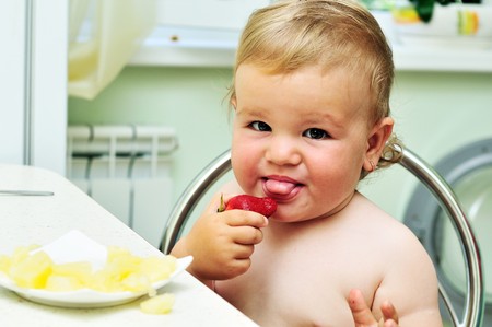 little funny baby girl tasting fresh strawberryの写真素材