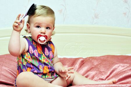 baby girl using comb at home on the bedの写真素材