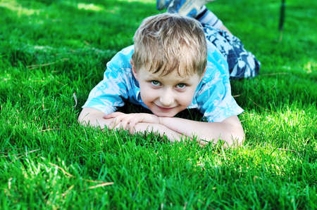 little blonde  boy laying on the sunny meadow の写真素材