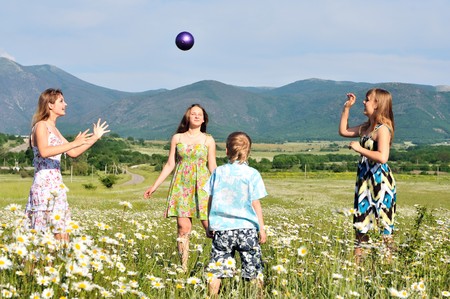 boy and teen girls playing a ball in field の写真素材