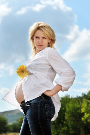 pregnant beauty woman relaxing outdoors with gerbera 