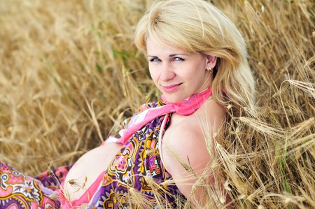 blonde pregnant woman relaxing in the wheat field の写真素材