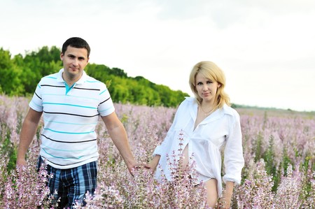 happy couple in waiting for baby walking in field の写真素材