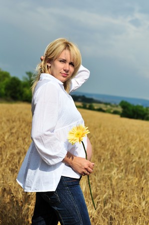 pregnant woman standing in summer sunny wheat fieldの写真素材