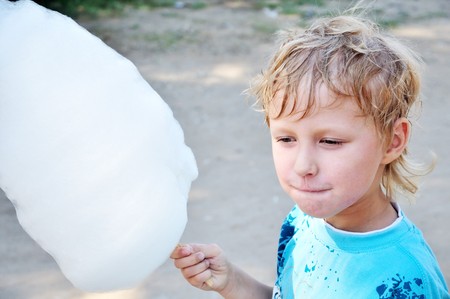 little boy holding cotton candy in hot summer day の写真素材