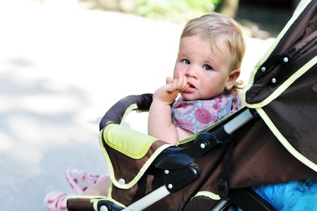 baby girl in the pram licking fingerの写真素材