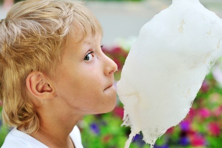 funny dirty face of little boy eating sweet cotton candyの写真素材