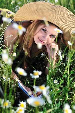 teen girl reading a book on the daisy meadow の写真素材