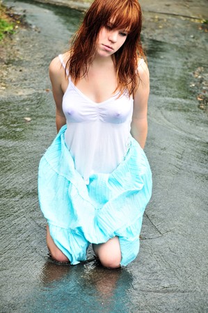 redheaded wet girl sitting in the puddleの写真素材