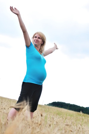pregnant happy woman enjoying weather in the fieldの写真素材