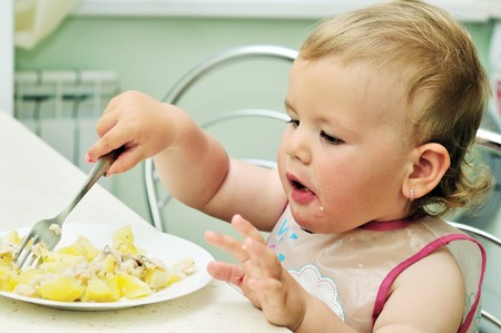 baby girl like eating with fork on her own の写真素材
