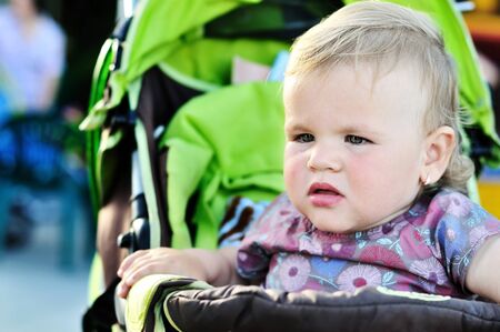 serious toddler girl sitting in the strolerの写真素材