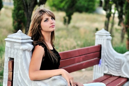Beautiful tanned girl sitting on the bench の写真素材