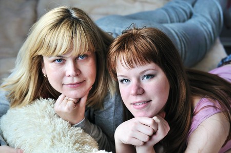 mother and teen daughter laying on the bed at homeの写真素材