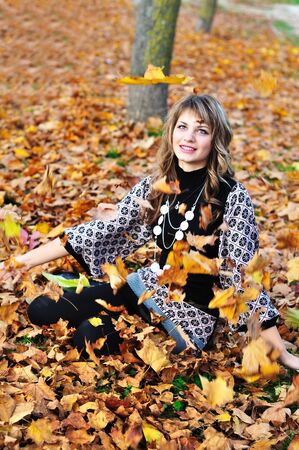teen girl throwing leaves up in the autumn parkの写真素材