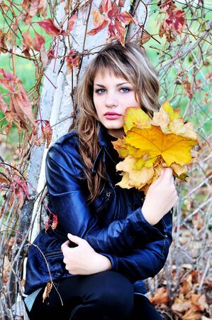 teen tender girl wearing leather jacket in the autumn parkの写真素材