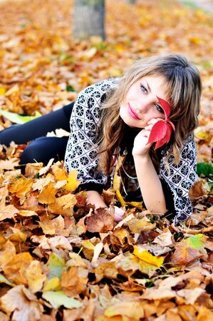 teen girl resting in foliage of autumn parkの写真素材