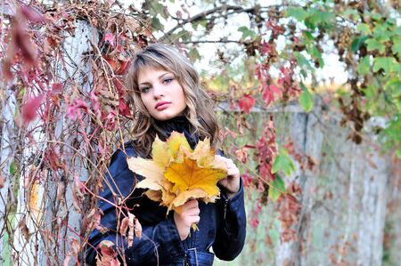 autumn pensive teen girl with foliage in handsの写真素材