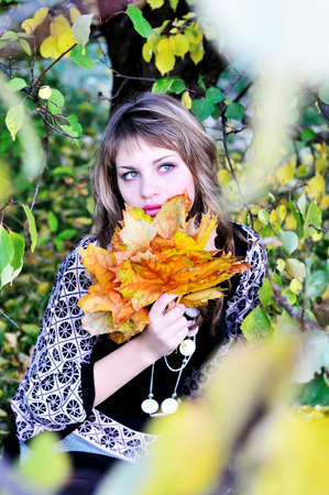 teen girl in forest holding foliage in autumn timeの写真素材