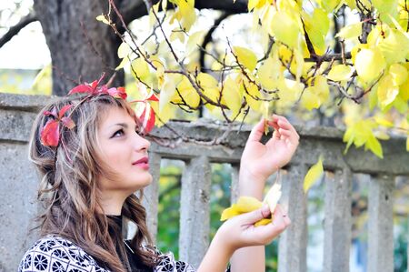 teen girl touching leaves in the autumn parkの写真素材