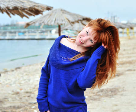 happy redheaded girl wearing blue sweaterの写真素材