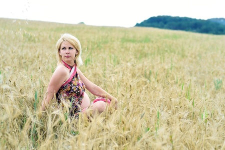  pregnant woman relaxing in the field of wheatの写真素材