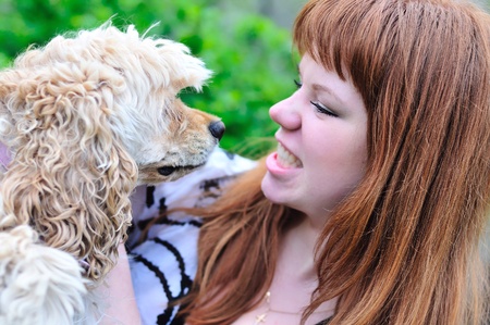 redheaded pretty girl having fun with her dog on the meadow の写真素材