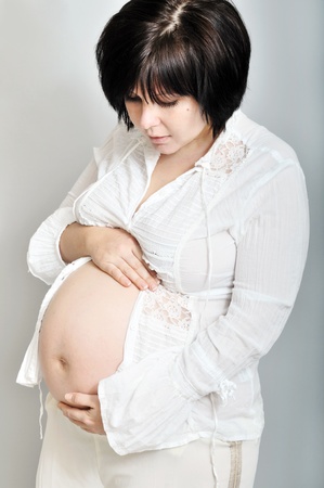 Beautiful pregnant woman holding her belly and dreaming of her babyの写真素材