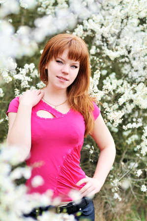 attractive redheaded girl standing in blossom garden の写真素材