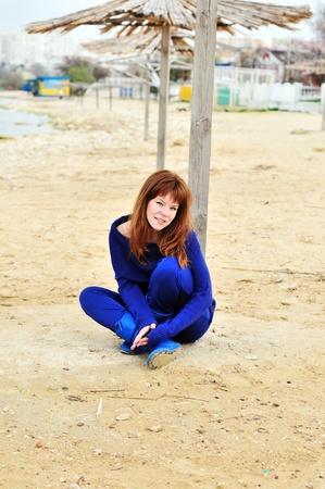 redheaded girl resting on the beach in spring time の写真素材
