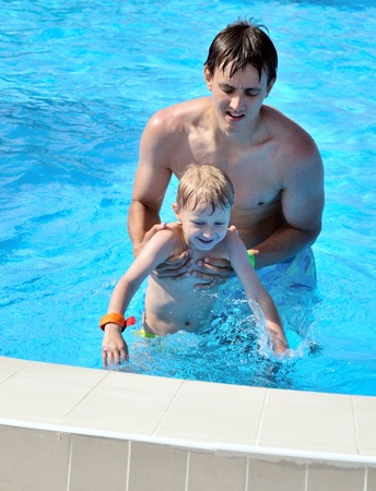 father and son having fun in water pool の写真素材