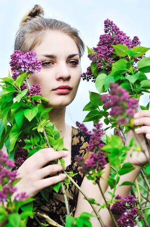 Beautiful teen girl smelling lilac blossomsの写真素材