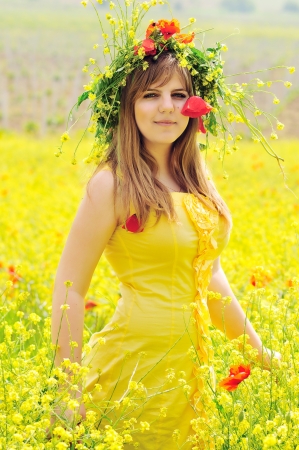 gril wearing yellow dress with wreath in fieldの写真素材