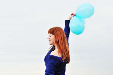 redheaded girl with balloons over the   sky の写真素材