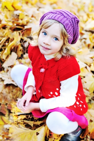 little blonde girl sitting in foliageの写真素材