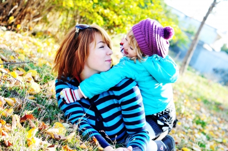 mother with daughter having fun in autumn parkの写真素材