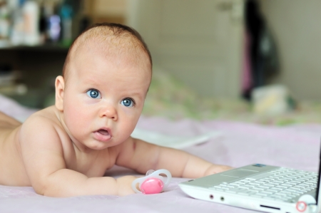 three months baby with laptop at homeの写真素材