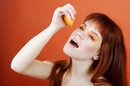 redheaded young woman enjoying of orange fresh juiceの写真素材